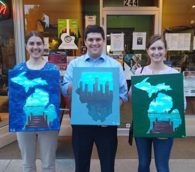 (Left to right) Gwen dePolo, Thomas Schmitt, and Rebecca Harmon working with paint in a different way at the 2019 American Chemical Society Central Regional Meeting. Photo courtesy of Rebecca Harmon.